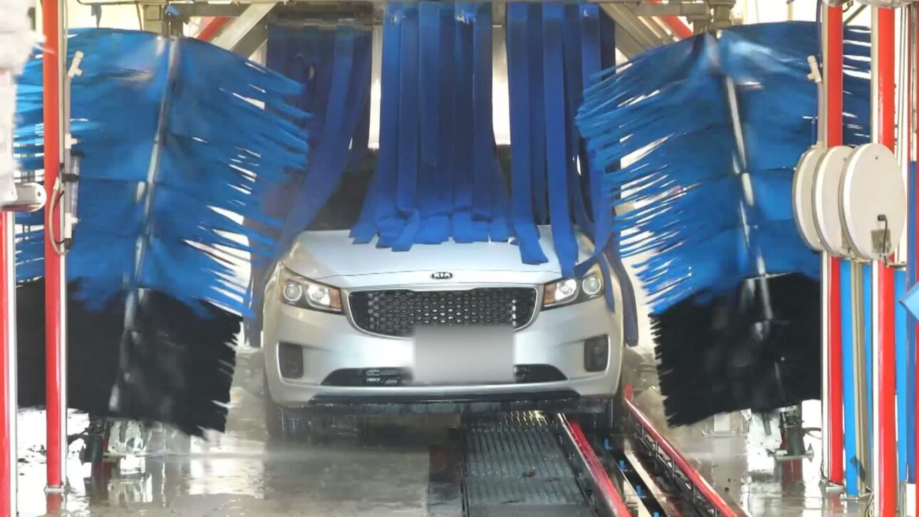 Silver Kia surrounded by blue brushes inside the Carwood wash tunnel